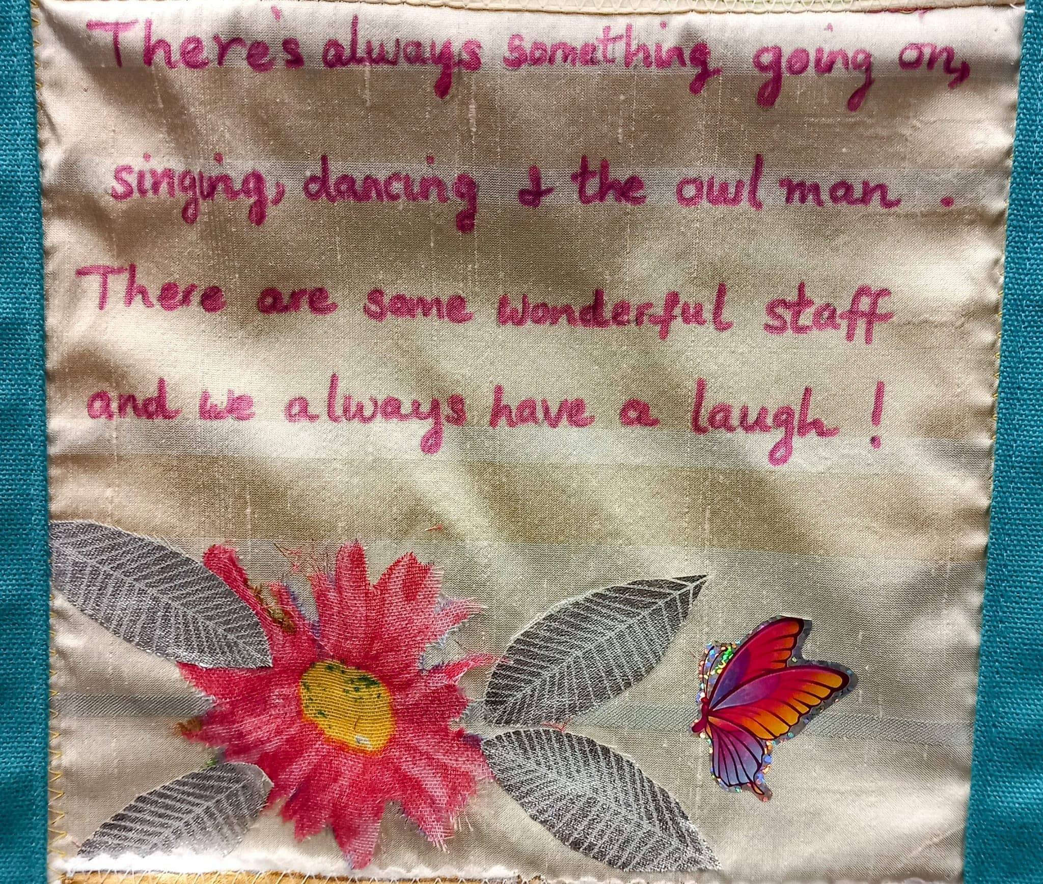 This fabric square features handwritten text about activities and the friendly staff at Abbeyfield, beautifully set over a large pink flower and a colourful butterfly.