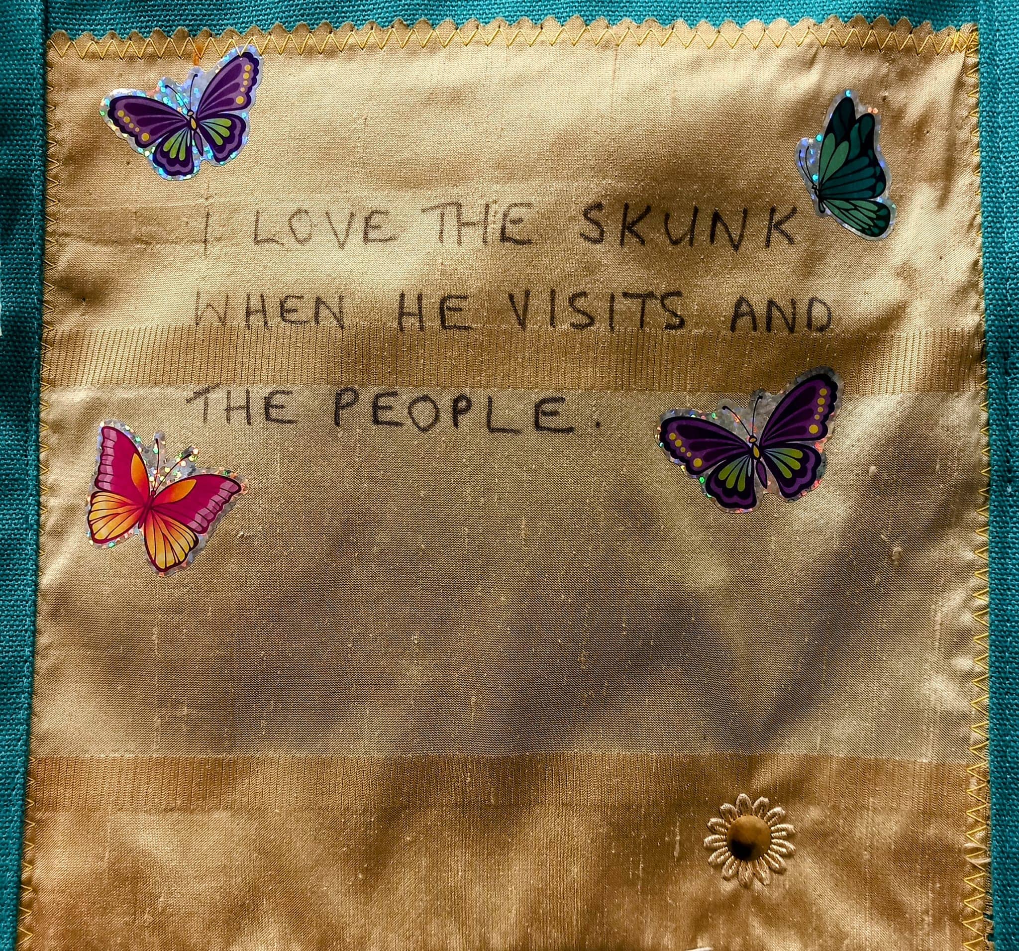 Text on a fabric background adorned with butterfly and floral stickers, reading: I love the skunk when it visits at the abbeyfield and the people.